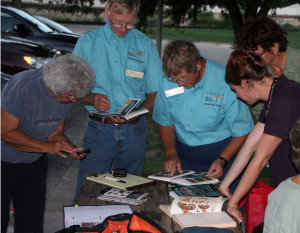 Central Texas Master Naturalists looking through Moth Guides trying to identify moths.