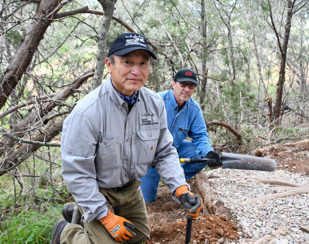 2 men next to gravel with tools for trail making
