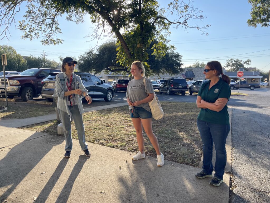 three women talking and standing on a sidewalk
