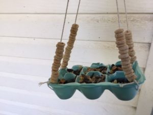 A bird feeder made with egg carton and decorated with cereal. 